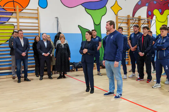 Reprezentanți ai campaniei și sportivi discutând cu elevii în sala de sport